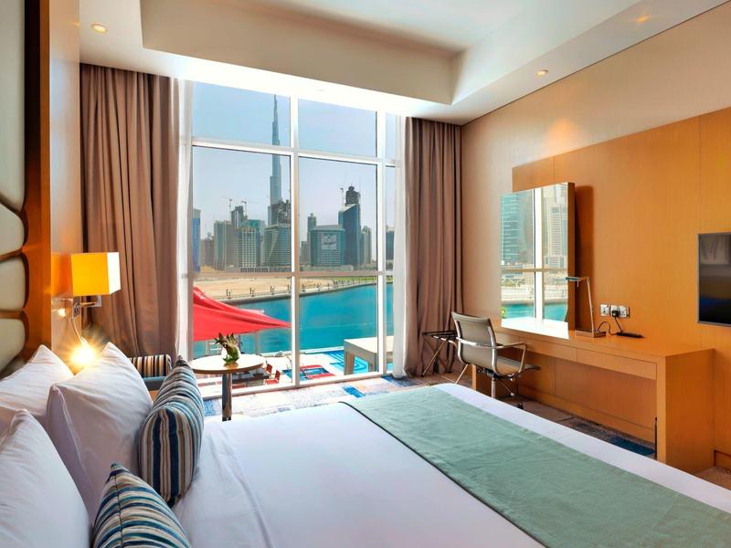 Modern hotel room with large window, sea view, and elegant interior.
