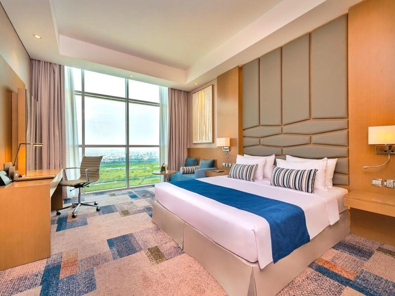 Modern hotel room with large window overlooking a golf course.