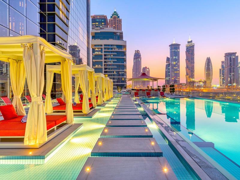 Luxurious hotel pool with seating areas and city view at sunset.