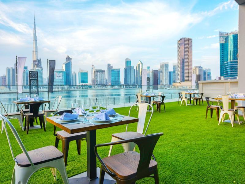 Terrace restaurant with skyline view and artificial green lawn.