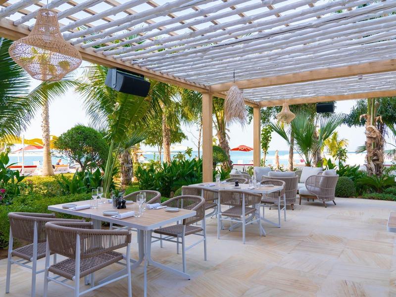 Beach with white sandbanks, turquoise water, and a pier in a tropical vacation spot.
