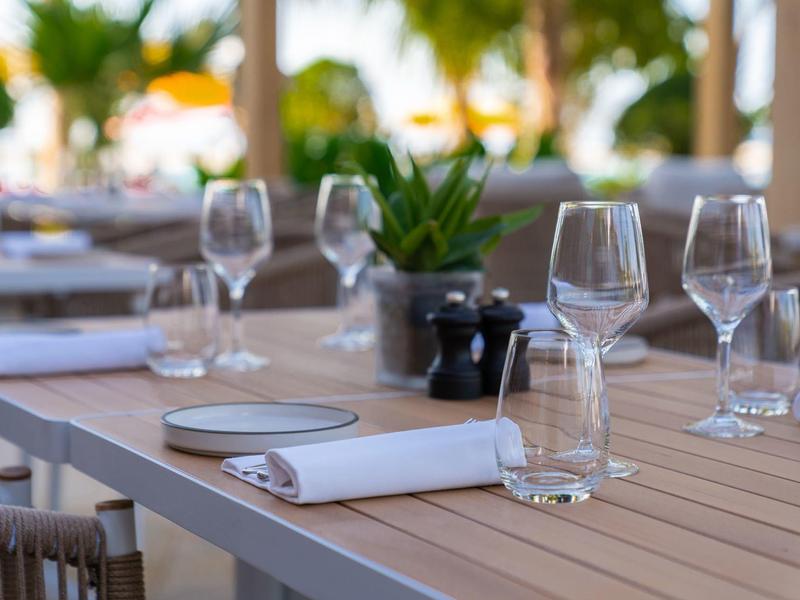 Set table with glasses, plates, and napkins in an outdoor restaurant.