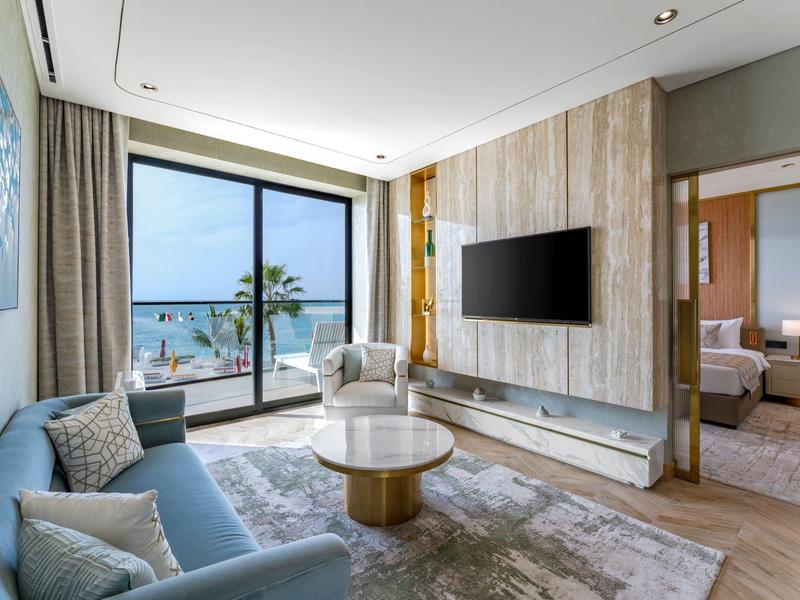 Modern living room with sofa, armchairs, large window, and sea view.