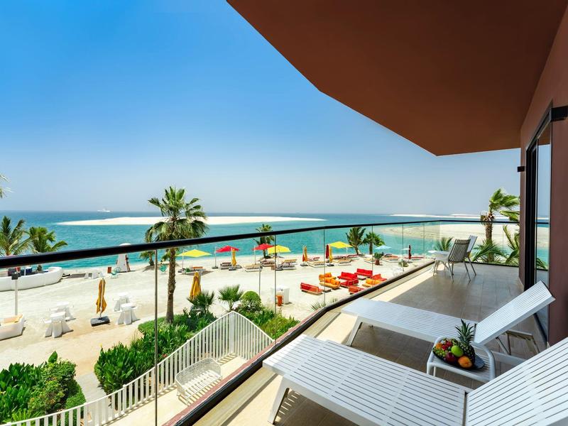 Balcony with lounge chairs and sea view at a sunny beach hotel.