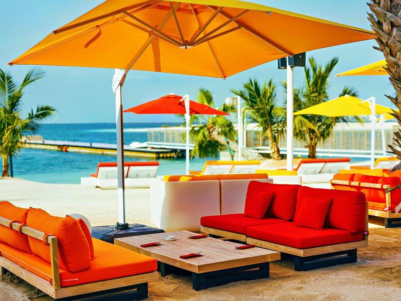 Colorful sofas and umbrellas on the beach with sea view on a sunny day.