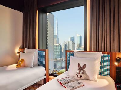 Schlafzimmer mit zwei Einzelbetten, braunen Vorhängen und Stadtblick durch großes Fenster.