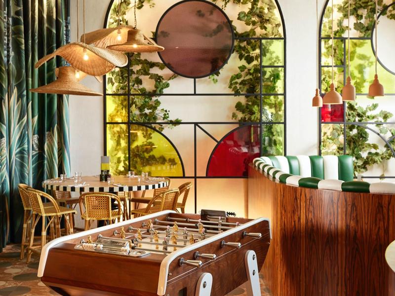 Modern lounge with foosball, bar, and colorful stained glass windows.