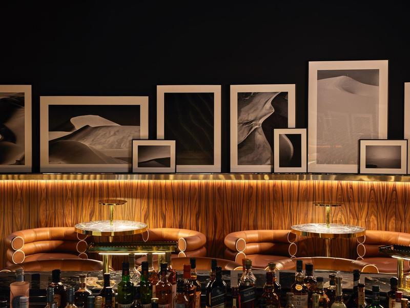 Modern bar with leather chairs and black-and-white desert photos on the wall