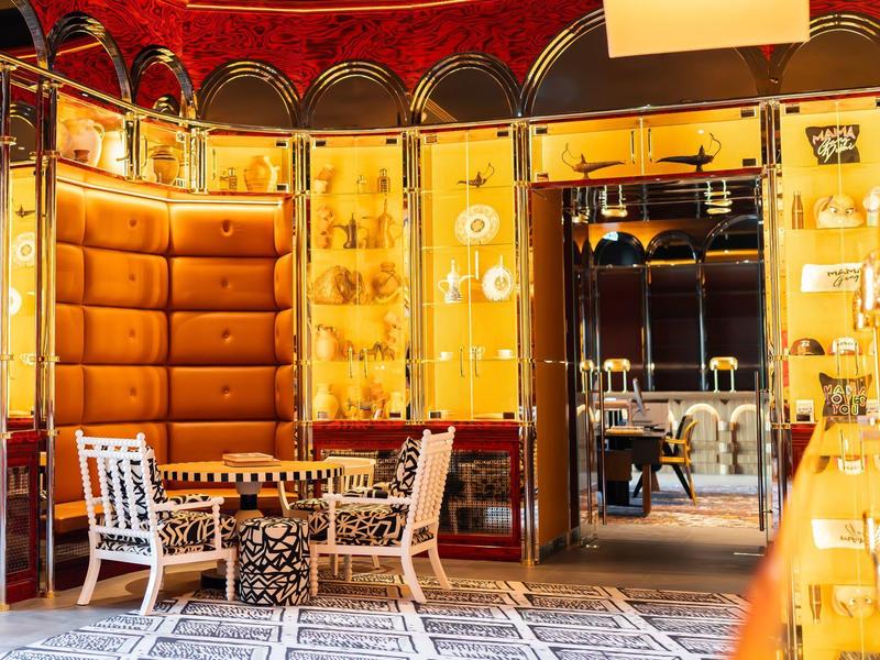 Elegant hotel area with padded seating, golden wall paneling, and stylish furniture.