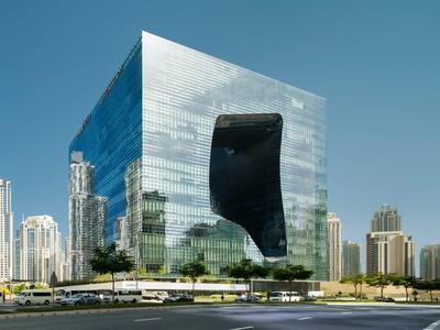Modern glass building with unique black design set against city skyline and clear sky.