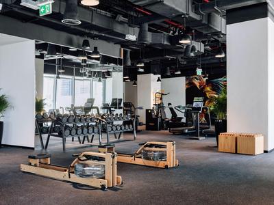 Interiér moderní posilovny s veslovacími stroji a činkami v hotelu.