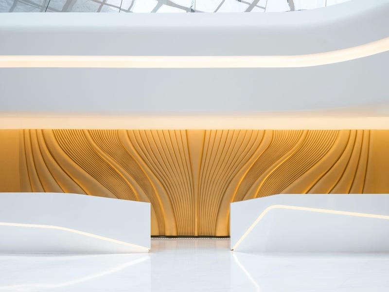 Modern seating area with white benches and wooden wall paneling beneath a skylight.