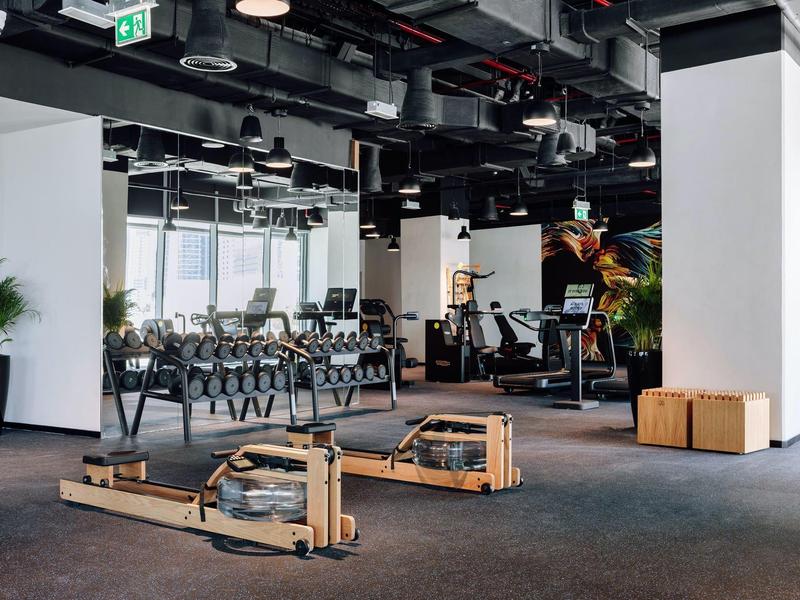 Spacious gym with rowing machines, weights, and cardio equipment in a modern hotel fitness area.