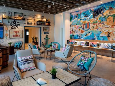 Cozy hotel lounge with colorful wall art, modern seating, and decorative plants.