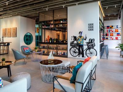 Moderne Hotellobby mit gemütlichen Sitzbereichen, Bücherregal und stilvoller Einrichtung.