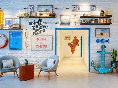 Heller Flur mit maritimen Dekorationen und zwei Sesseln vor einer weißen Wand.