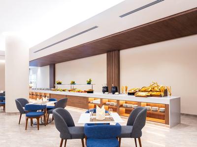 Moderní snídaňový bufet s posezením v elegantní hotelové restauraci.