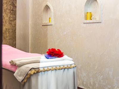 Pohodlná ošetřovna s masážním stolem a dekorativními ručníky pro relaxaci.