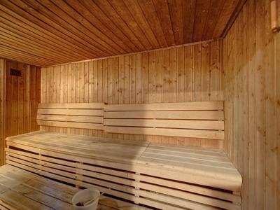 Interiér tradiční dřevěné sauny s postupnými lavicemi a dřevěnými stěnami.