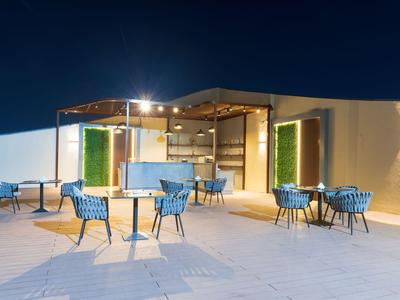 Osvětlený venkovní salon s židlemi a stoly na hotelové terase v noci