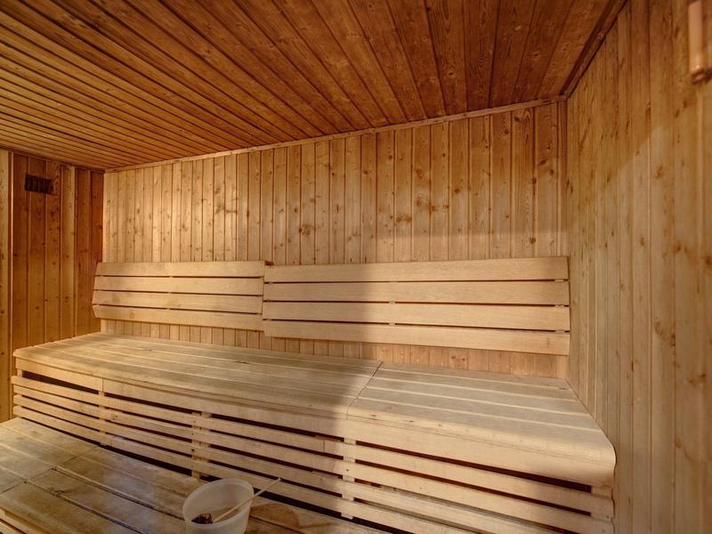Interiér tradiční dřevěné sauny s postupnými lavicemi a dřevěnými stěnami.