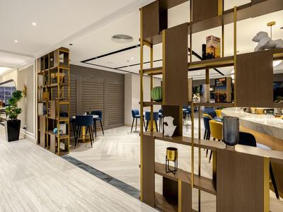 Área moderna del vestíbulo del hotel con estanterías de madera decorativas y asientos.