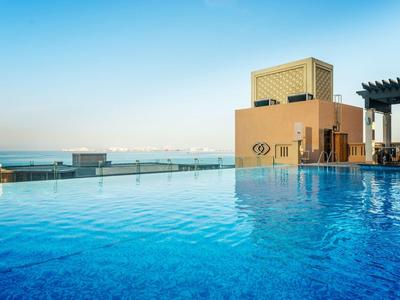 Piscina infinity con agua azul clara y vista al mar al atardecer.