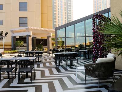 Lounge moderna de hotel con muebles negros y patrón geométrico en el suelo de la terraza.