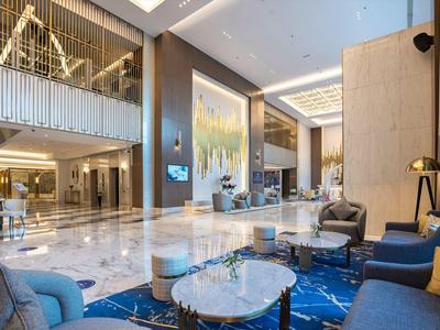 Lobby elegante del hotel con muebles modernos, suelo de mármol y luz cálida.