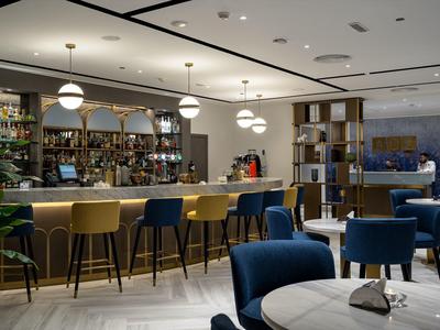 Bar moderna con taburetes coloridos y áreas de asiento elegantes en un entorno hotelero sofisticado.