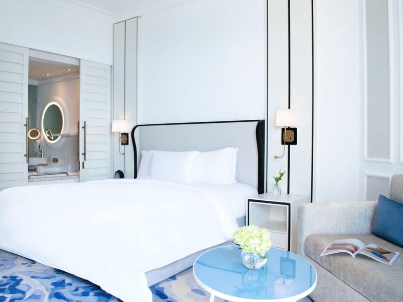 Habitación doble luminosa con cama grande, baño moderno y área de descanso cómoda.