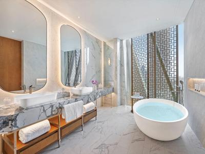 Luxurious bathroom with freestanding bathtub, two large mirrors, and marble vanity.