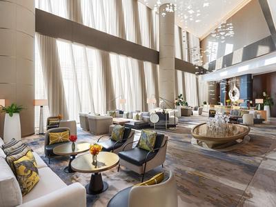 Luxurious hotel lobby with tall windows, modern interior, and cozy seating areas.