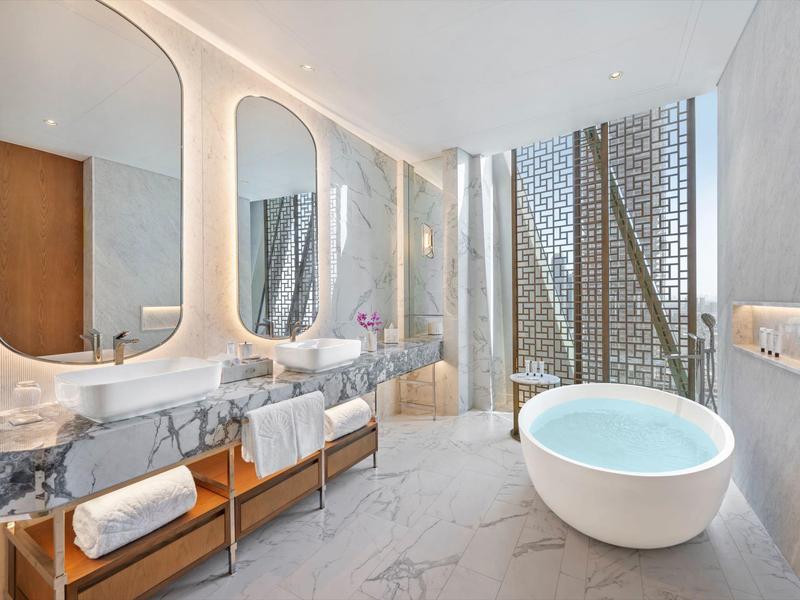 Luxurious bathroom with freestanding bathtub, two large mirrors, and marble vanity.