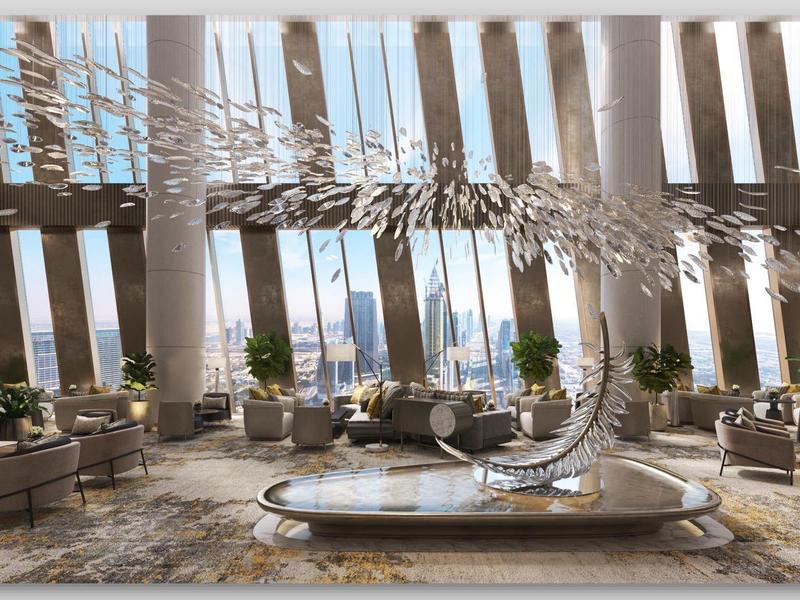 Spacious hotel lobby with tall windows, modern chairs, and abstract sculpture in the center.