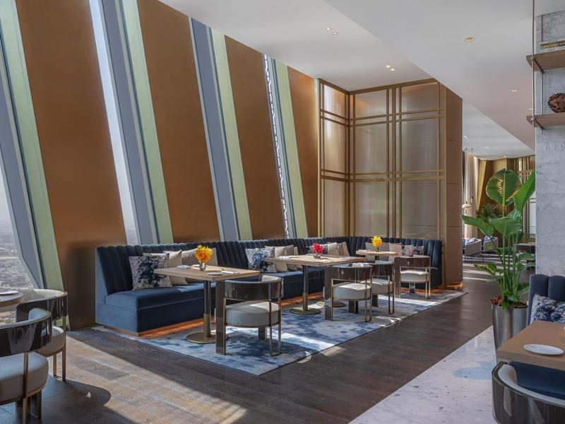 Modern dining area with wooden floors, dark blue benches, and colorful flowers on tables