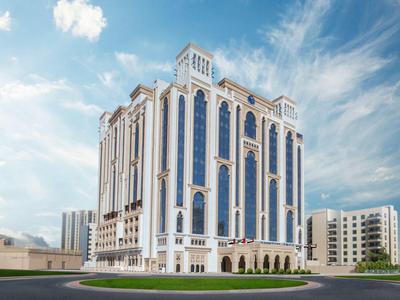 Tall modern hotel building with many large windows and blue sky in the background.