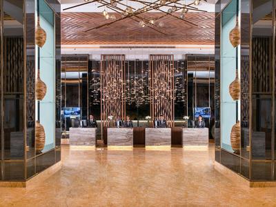 Luxurious hotel lobby entrance with gold and dark accents, marble floor, and decorative sculptures.