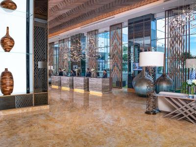 Elegant hotel lobby with marble floor, decorative vases, and large reception desk.