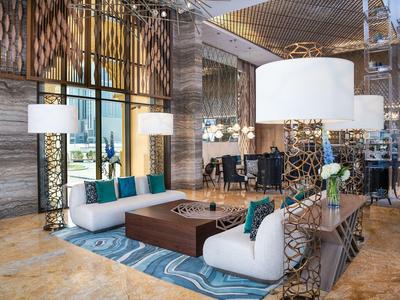 Modern hotel lounge area with comfortable seating, rug, and floor lamps.