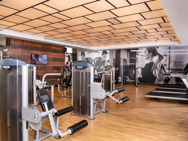 Modern gym with equipment and wooden floor in hotel setting.