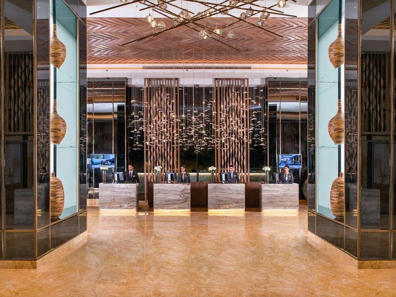 Luxurious hotel lobby entrance with gold and dark accents, marble floor, and decorative sculptures.