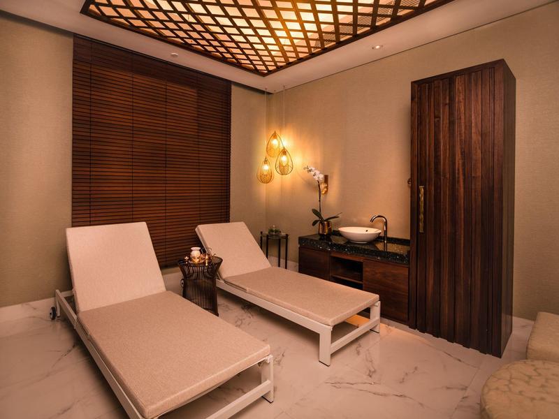 A tranquil spa room with two white lounge chairs and warm wooden decor.