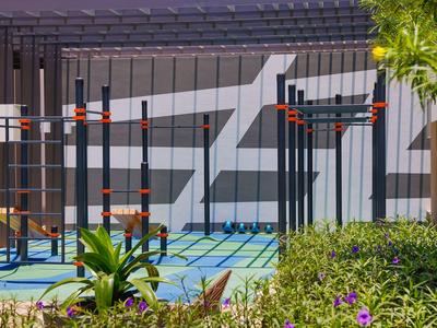 Nowoczesny teren fitness na zewnątrz z drążkami wspinaczkowymi przed szarą ścianą z nadrukiem graficznym