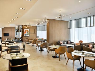 Nowoczesne wnętrze restauracji hotelowej z stolikami i różnorodnymi miejscami do siedzenia.