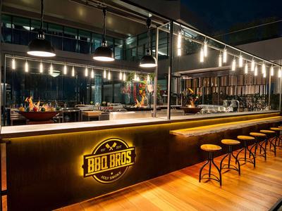 Moderne Bar im Freien mit industriellen Stühlen und indirekter Beleuchtung bei Nacht.