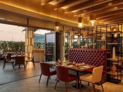 Modernes Restaurant mit Holzdecke, bequemen Stühlen und Blick auf eine Terrasse.