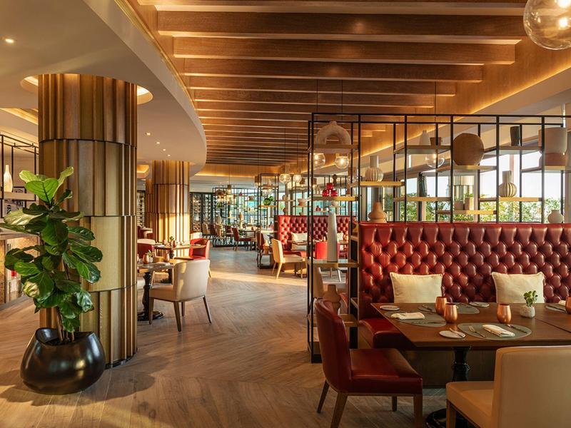 Elegantní hotelová restaurace s dřevěným trámovým stropem a červenými sametovými židlemi