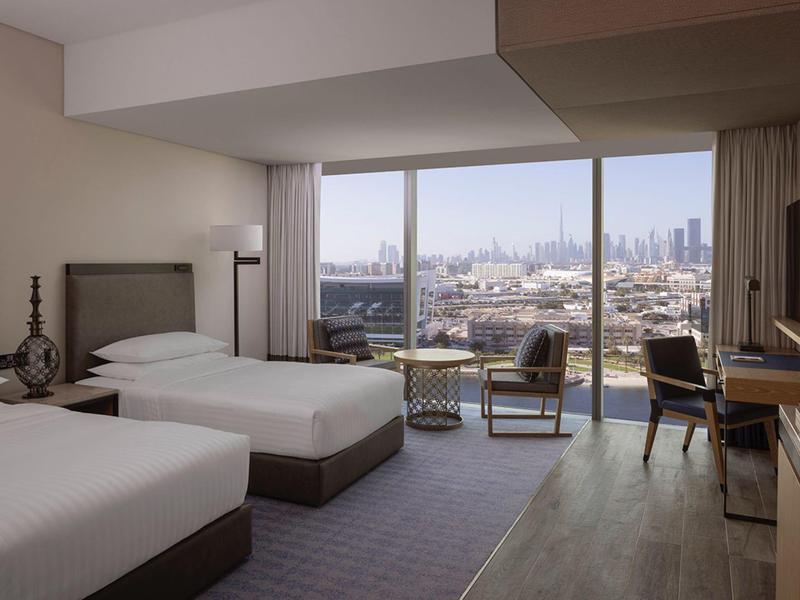 Hotelový pokoj se dvěma postelemi, balkonem a výhledem na město.