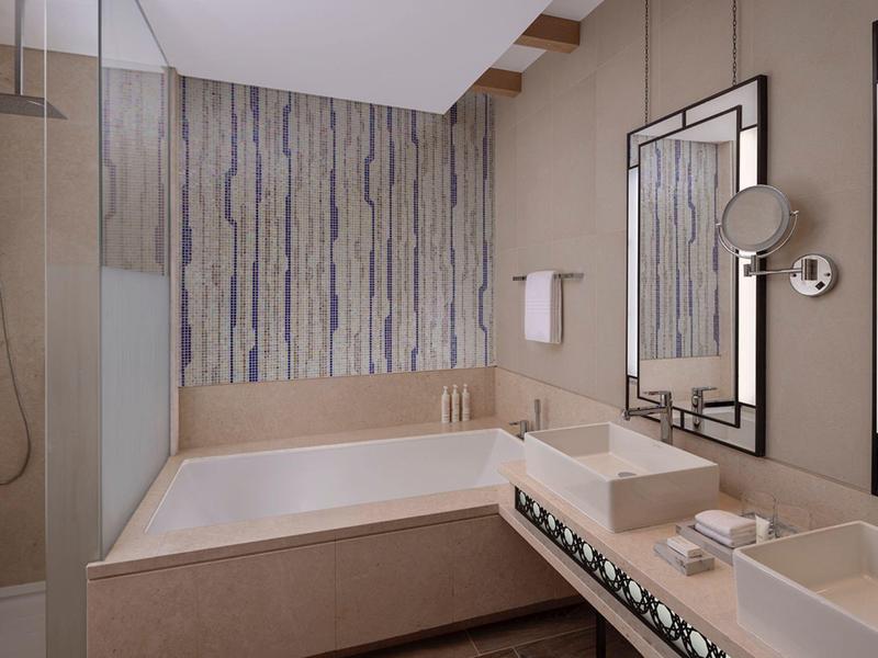 Moderní koupelna s velkou vanou, dvěma umyvadly a dekorativním zrcadlem.